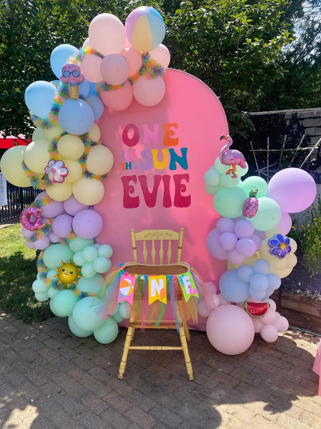 Pastel balloon garland climbing a pink arch backdrop for a first birthday, first birthday balloon arch Rochester NY