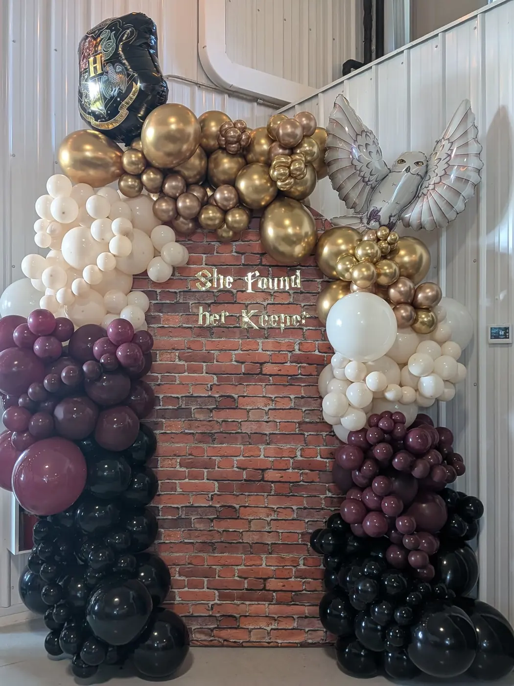 Burgundy, ivory and gold balloon garland framing a brick wall backdrop, bridal shower balloons Rochester