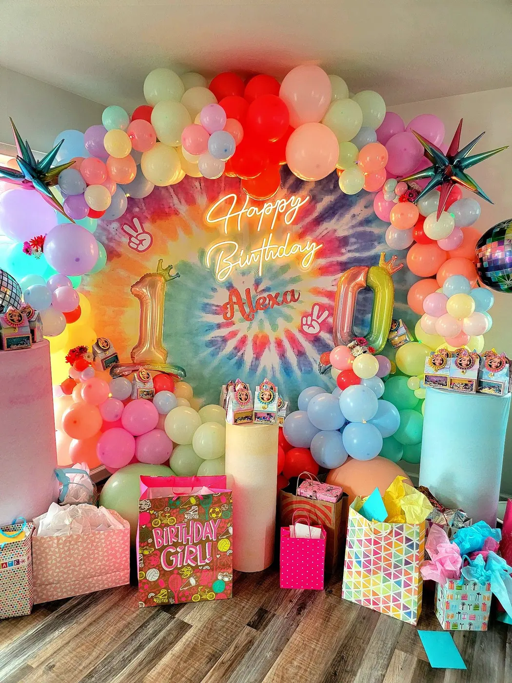 Rainbow balloon garland around a tie-dye birthday backdrop with gifts, by Balloon Events by Gigi, Rochester NY